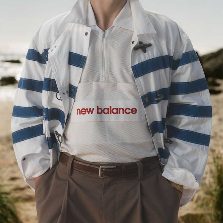 A man standing on a beach with his hands in his pockets. 