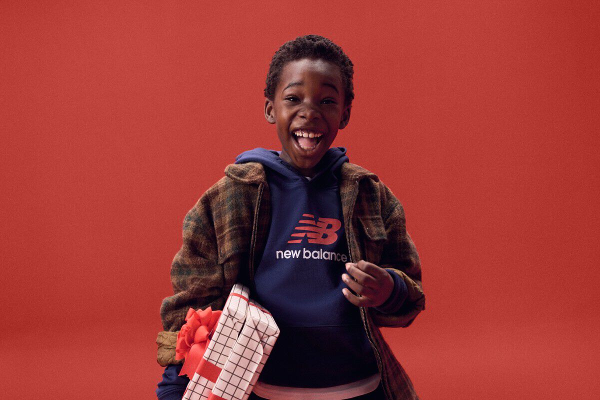 Kid laughing while holding gifts on a red background.