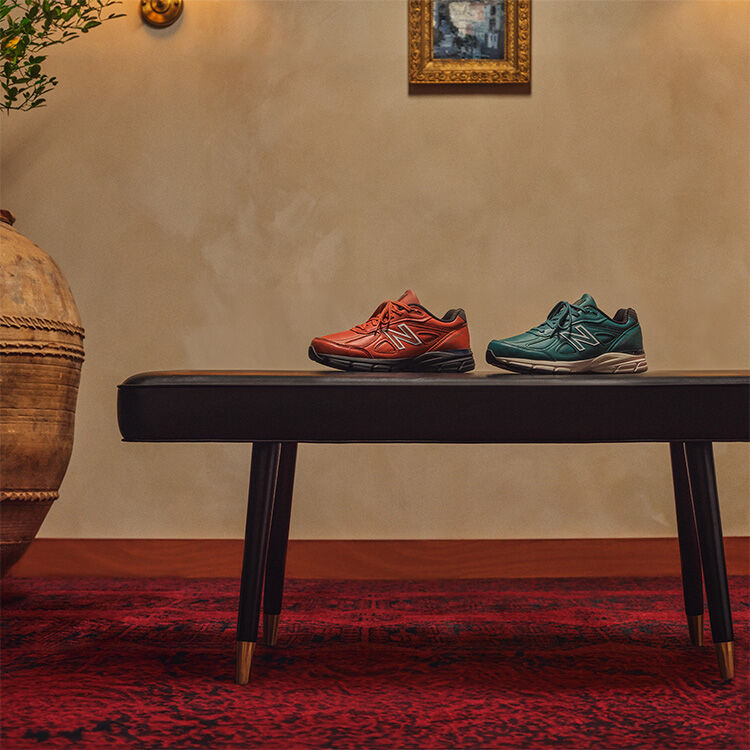 New Balance MADE in USA shoes, apparel, and boxes sitting or hanging on a gold luggage cart in a beautiful indoor environment.