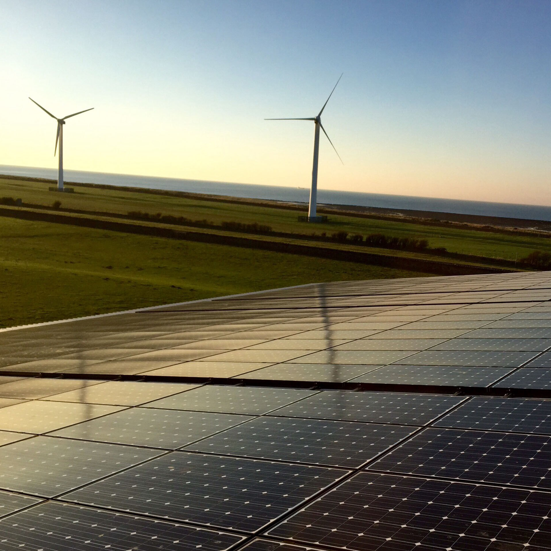 Solar panels and windmills against a blue sky